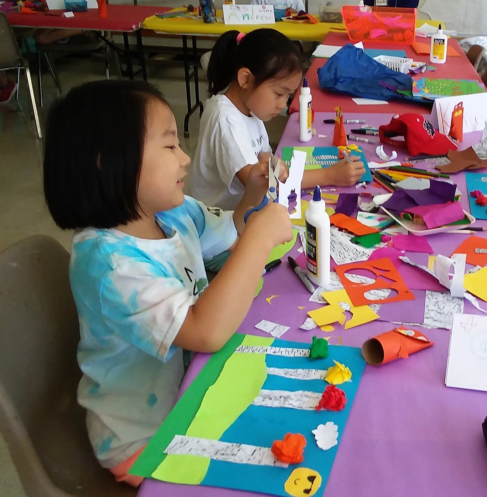 Two girls cut paper for collages.