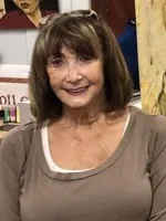 Woman smiles wearing a brown shirt.