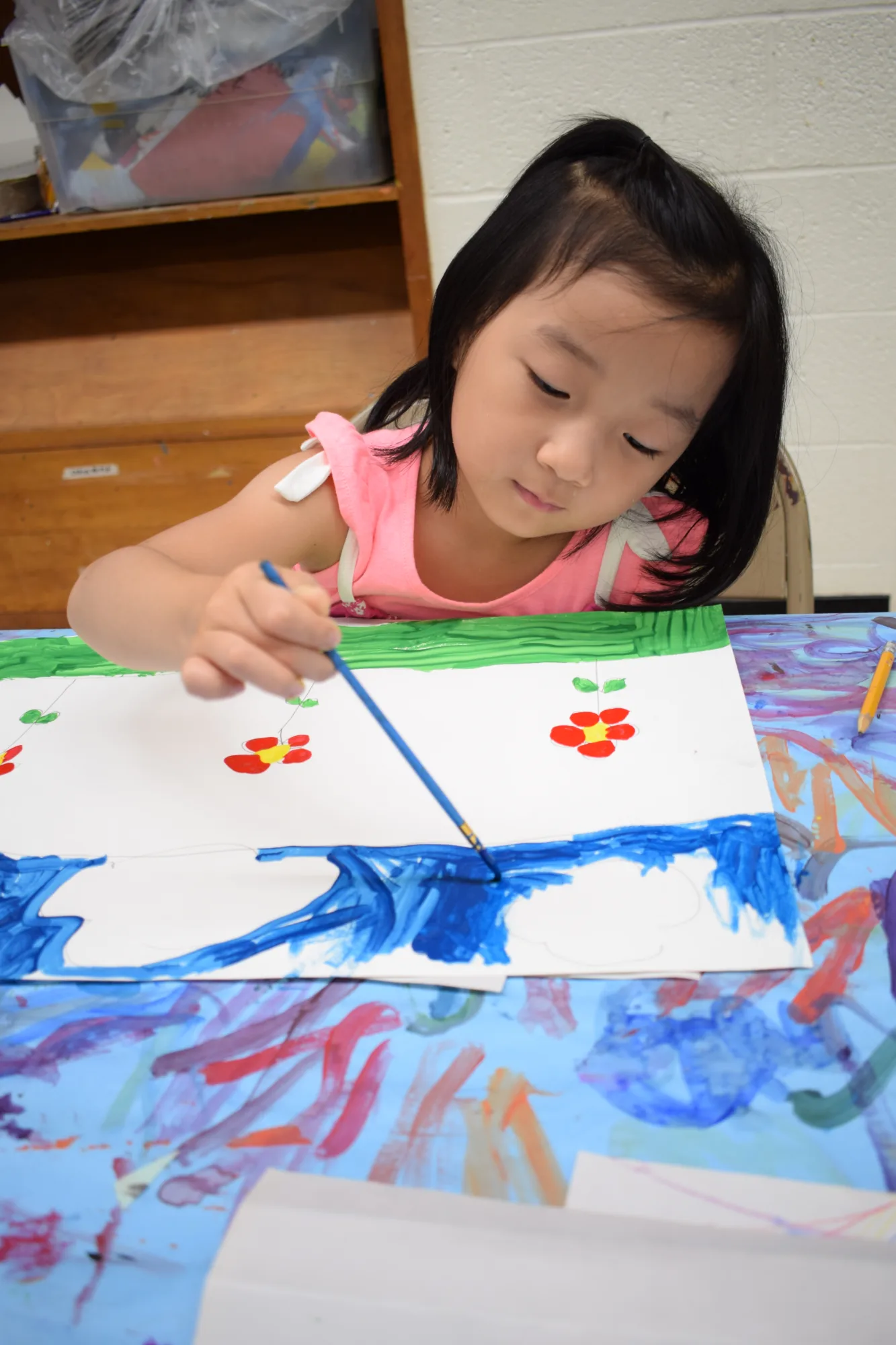 Child painting flowers onto a piece of paper