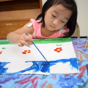 Child painting flowers onto a piece of paper