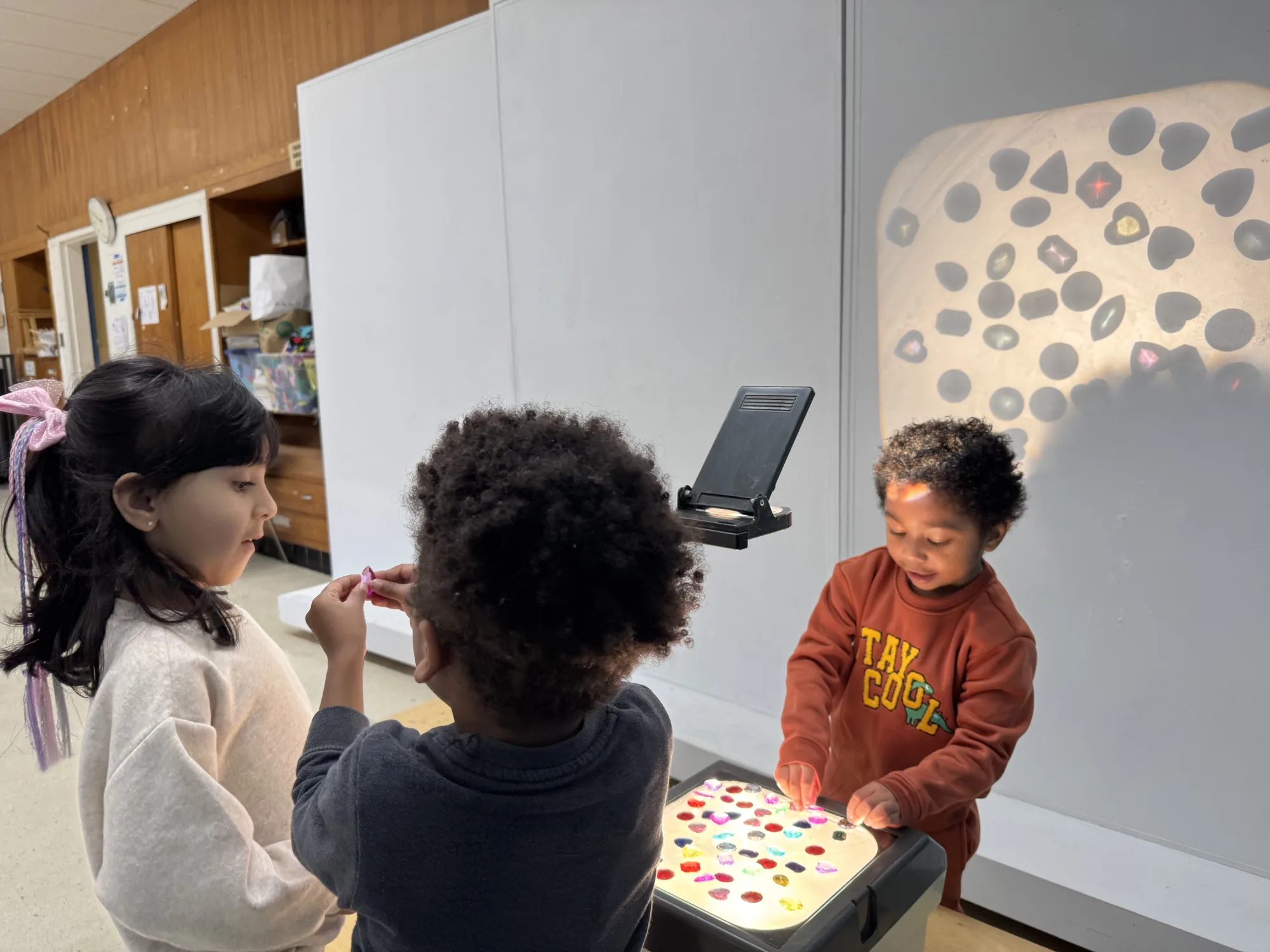 Children place objects on an overhead projector.