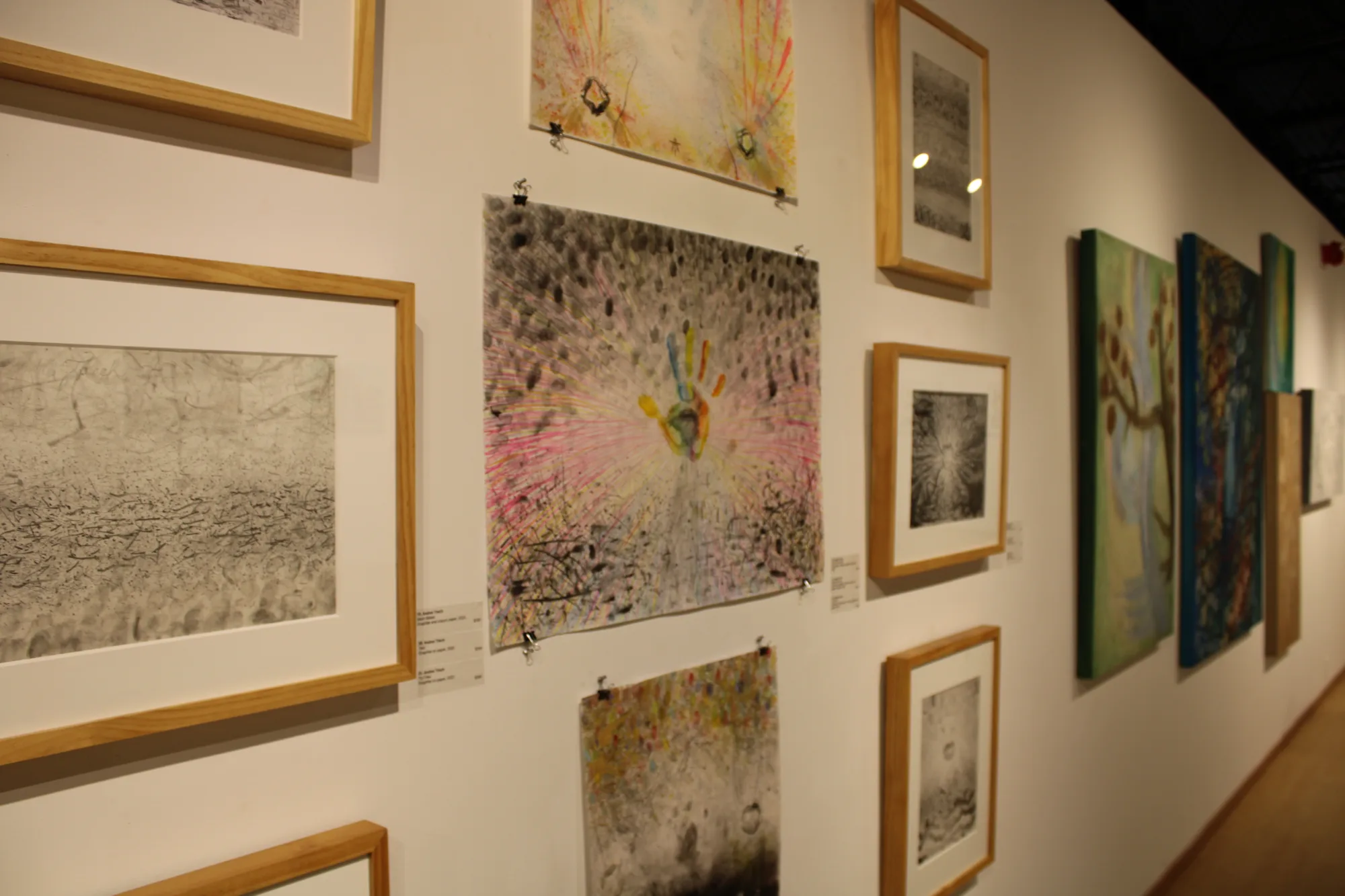 Collections of artwork hung on display along left wall.