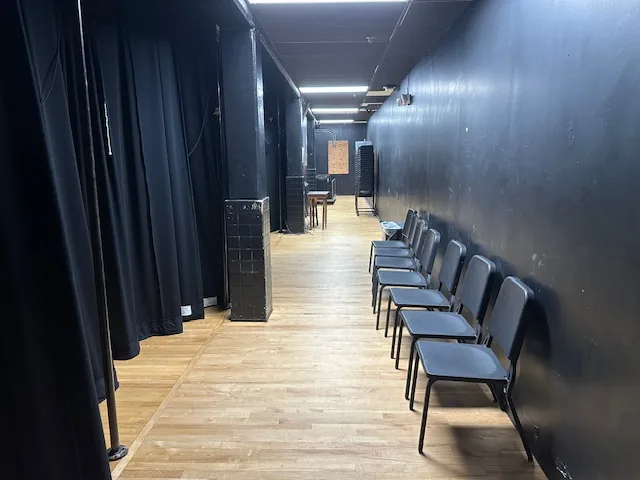 Empty backstage area with black chairs in a row