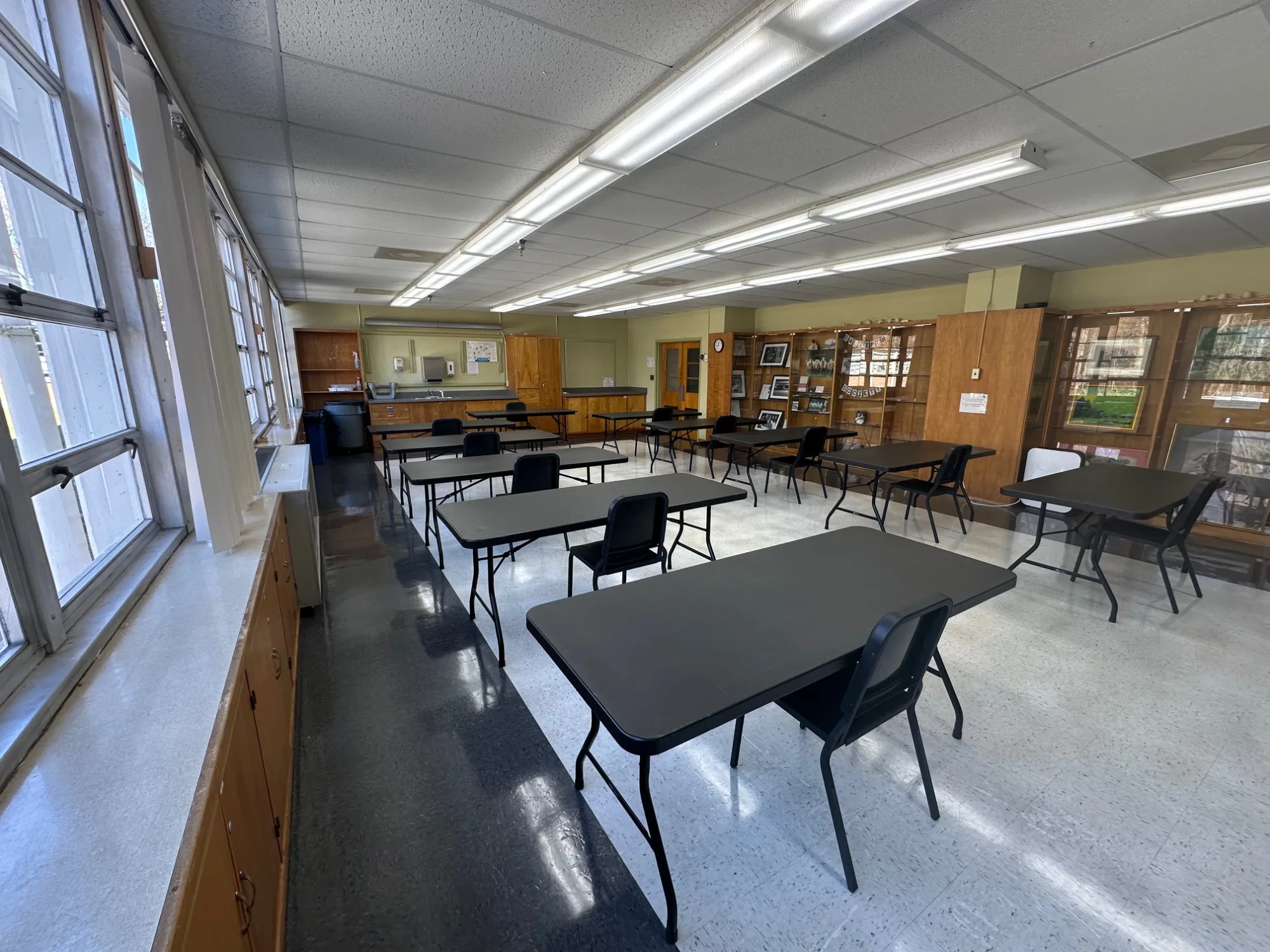 Empty room with black tables set up in long rows and chairs on either side