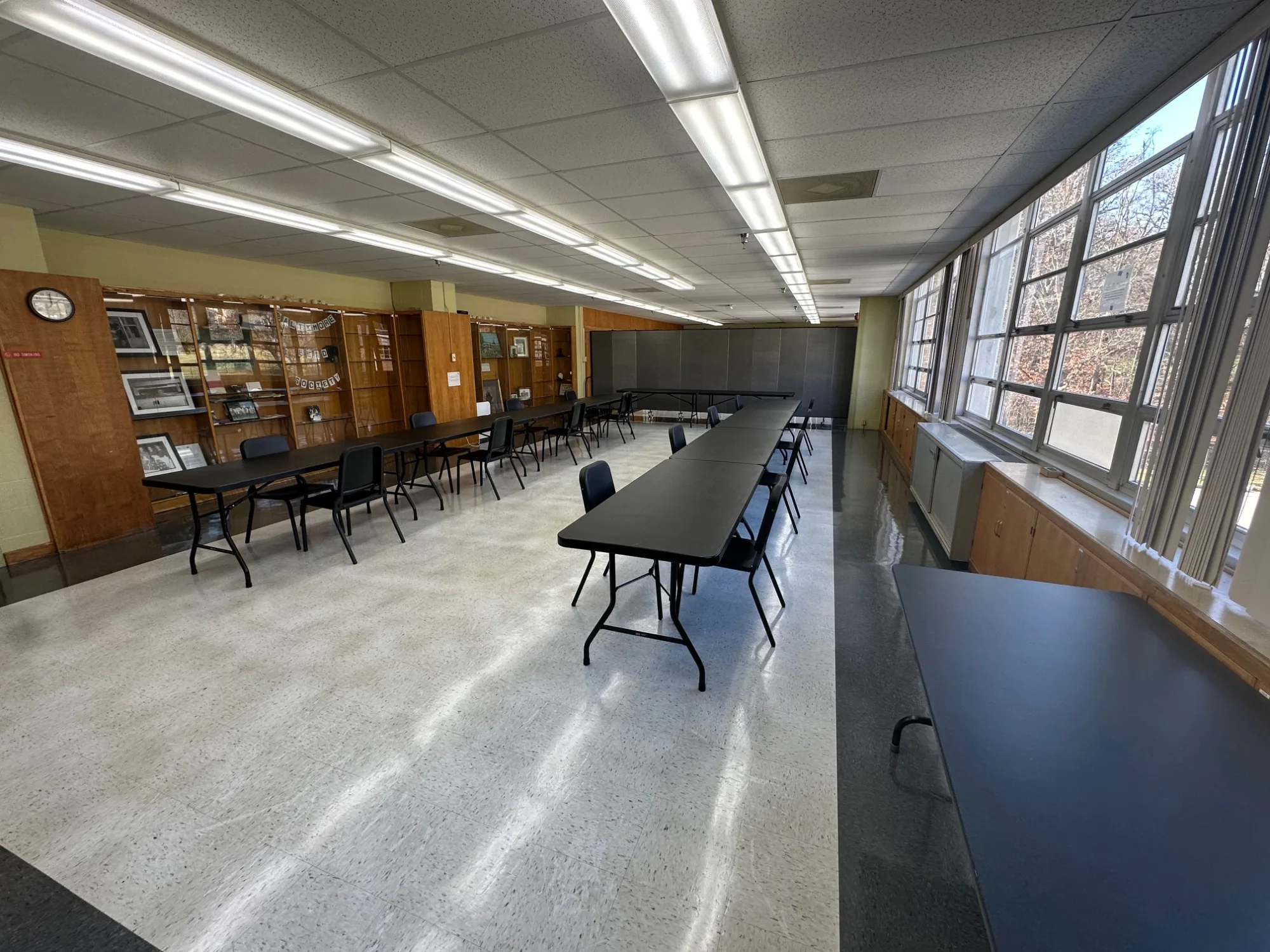 Empty room with black tables set up in long rows and chairs on either side