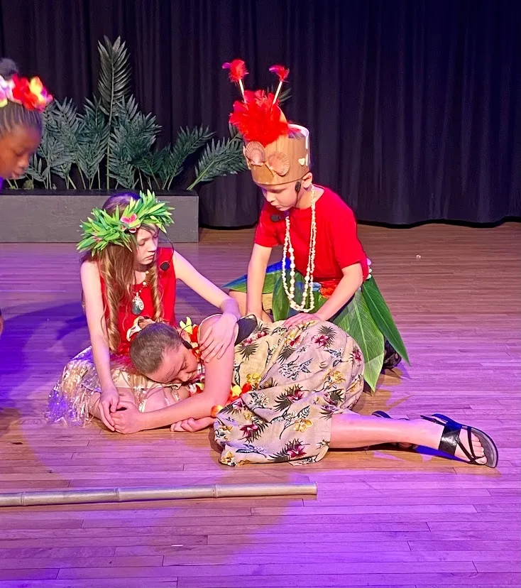 Three children staging a scene in costume with theatre lights