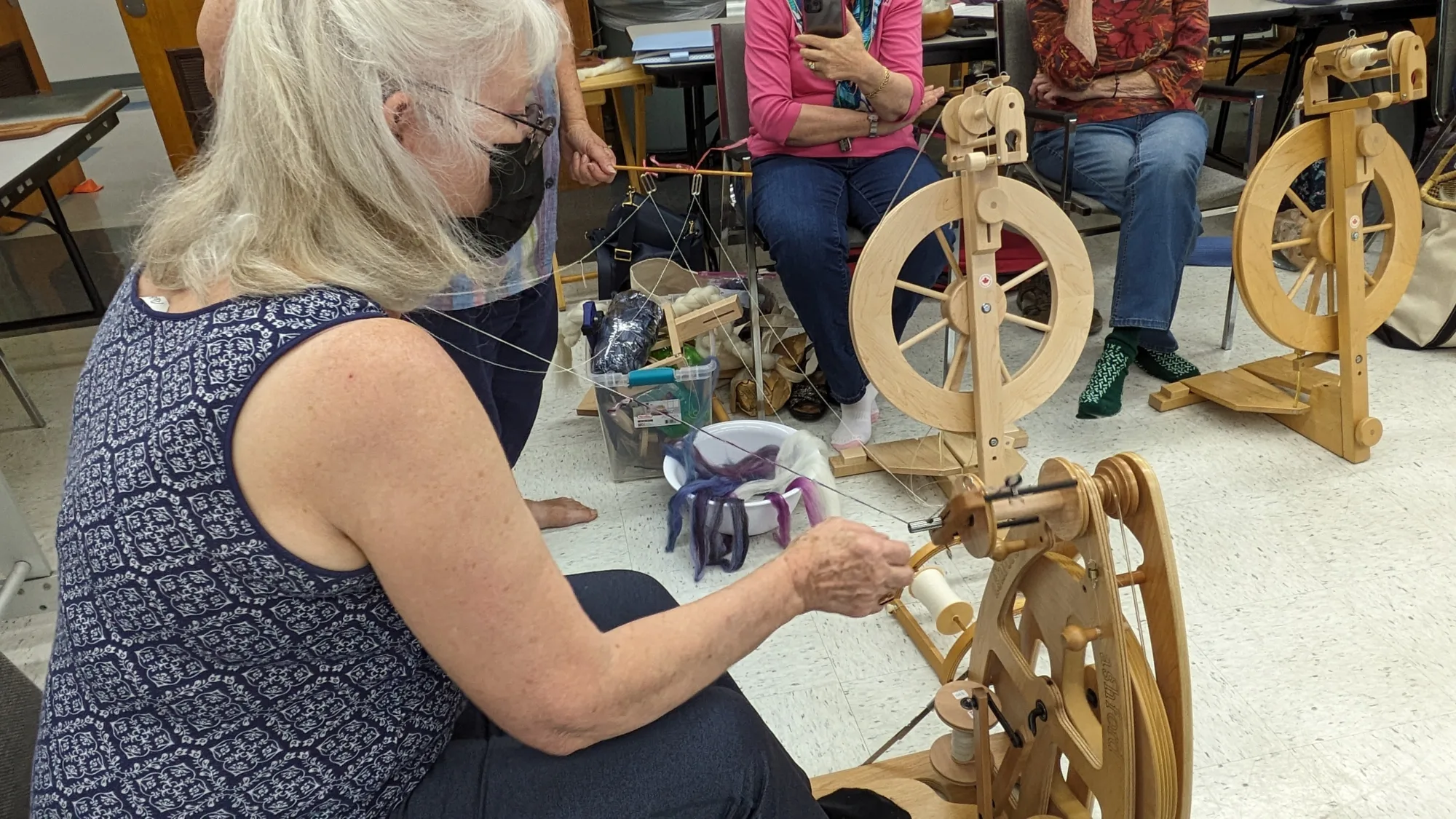 A woman using a wooden spinning wheel