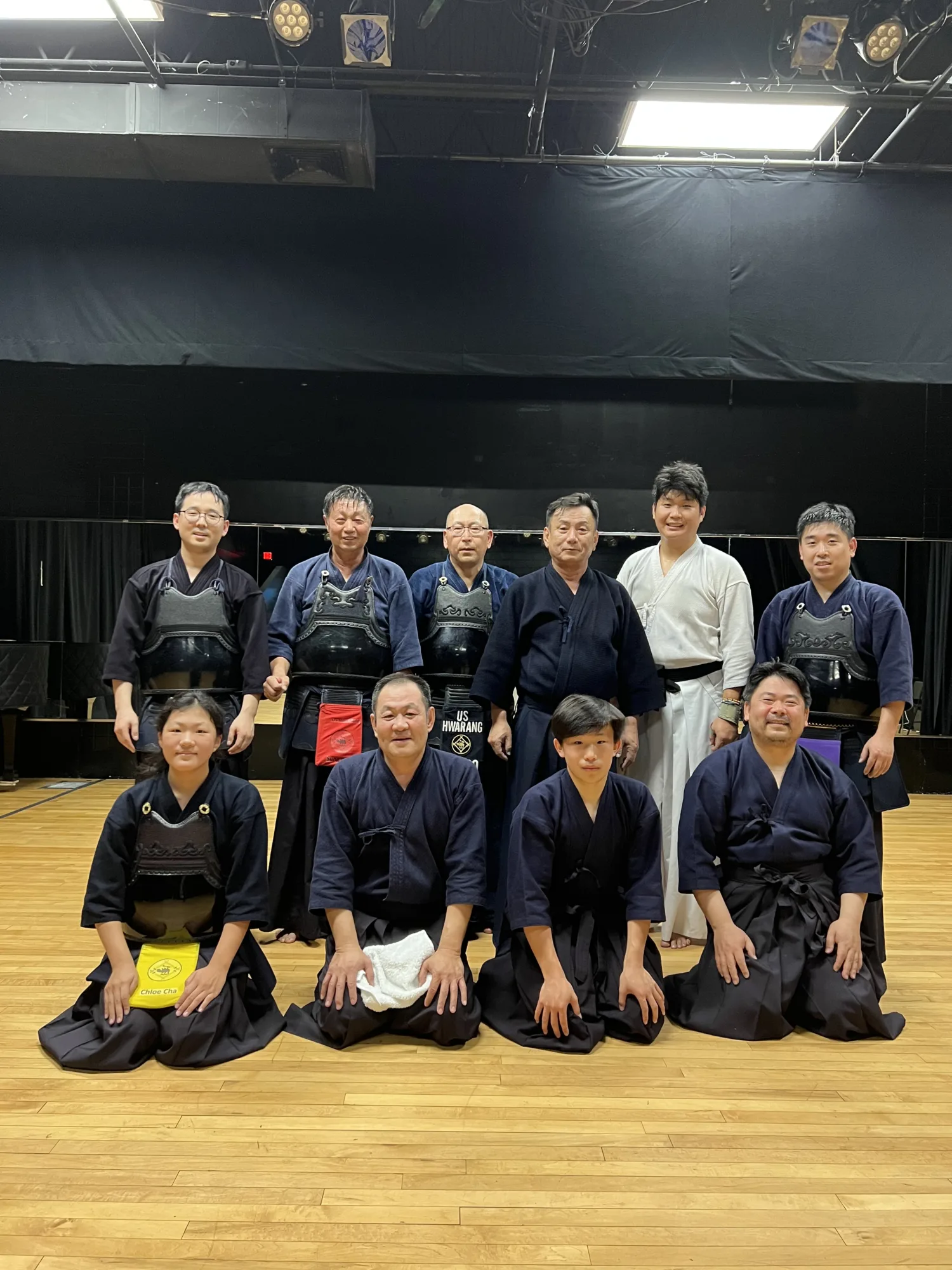 Group of martial arts students and teachers posed in front of theatre curtains