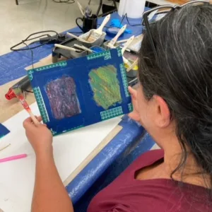 A person holds their artwork in their hands and looks at it.