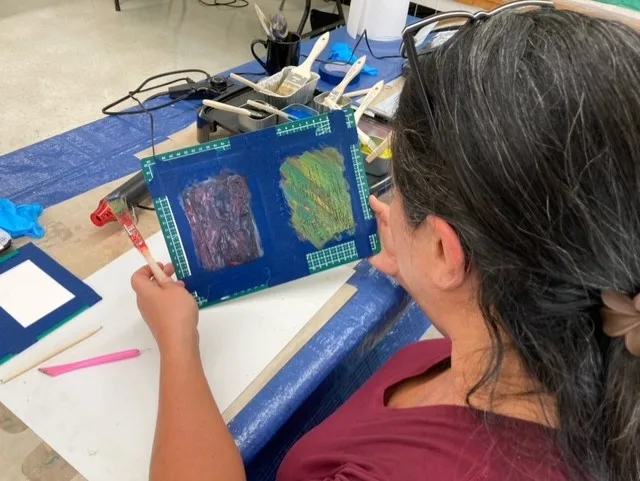 A person holds their artwork in their hands and looks at it.