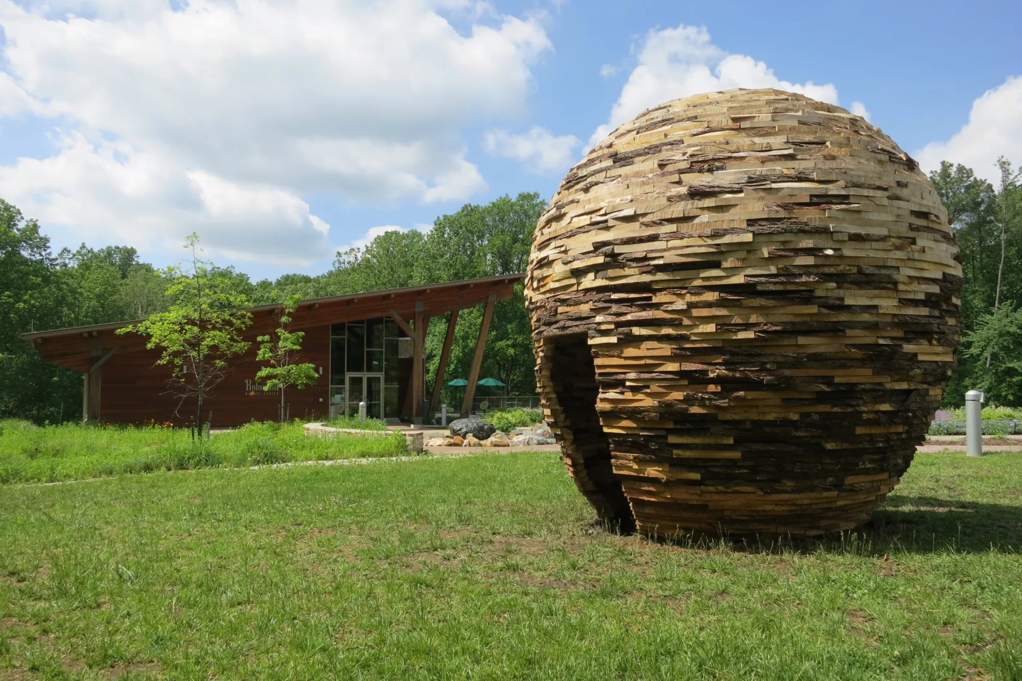 Large wooden beehive sculpture installed on lawn of nature center.