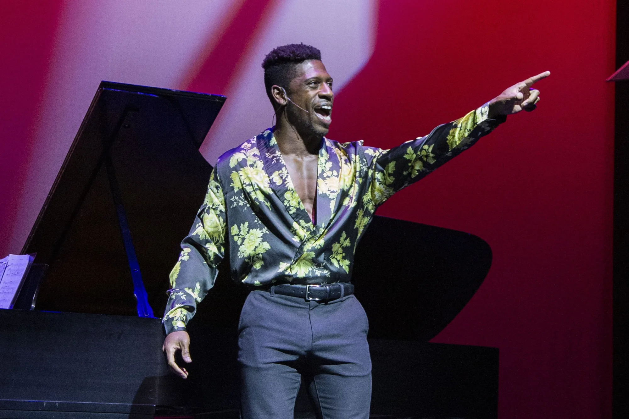 A man singing on stage points into the distance