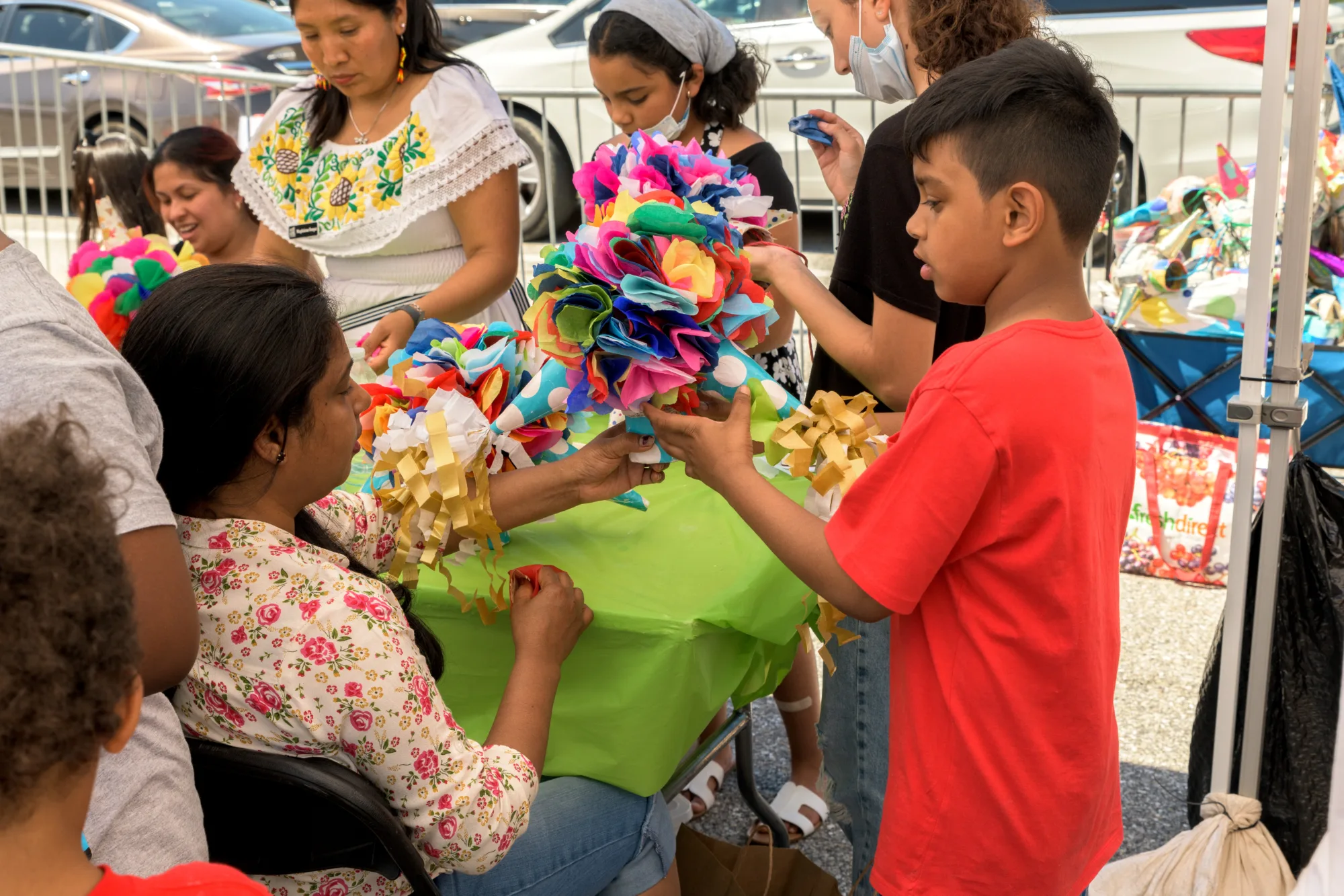 People make colorful pinatas at an outdoor arts festival.