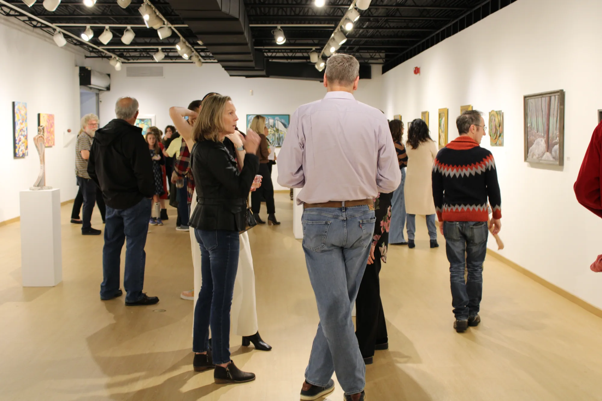 Visitors socialize inside the gallery as they view the artwork.