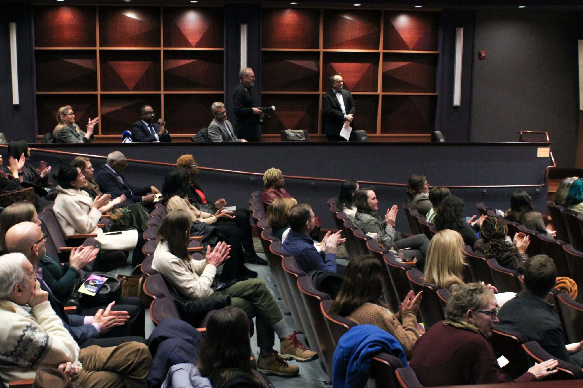 Audience listens in speakers in theater