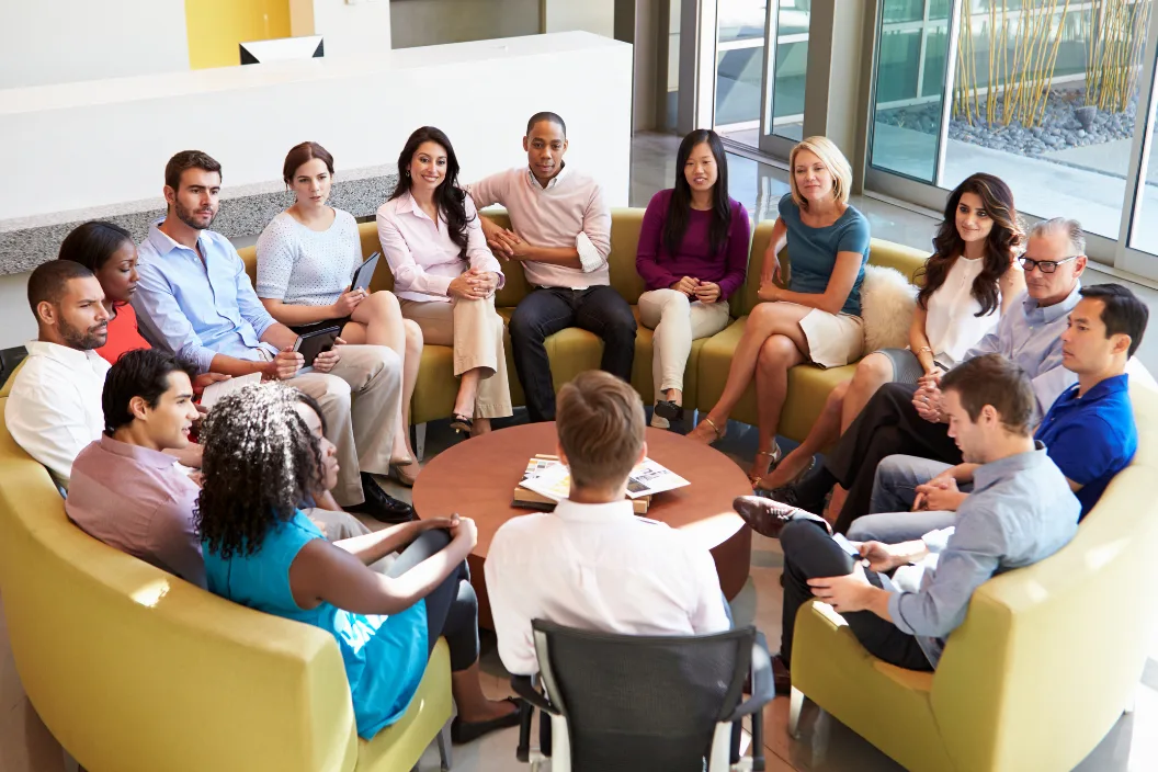 Group of people sit in a circle listening to a speaker