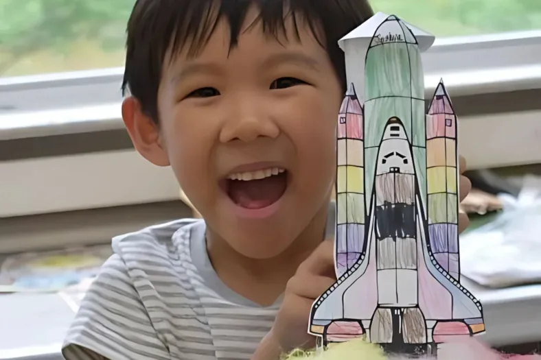 child with a paper space shuttle