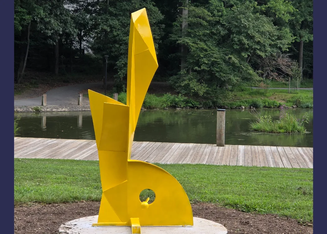 large yellow sculpture in front of a body of water