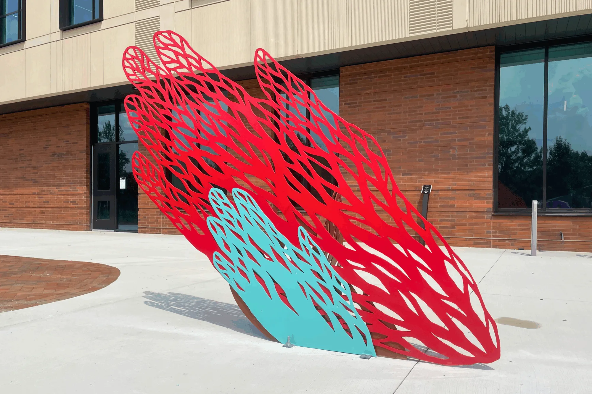 red and blue wing sculpture in front of building