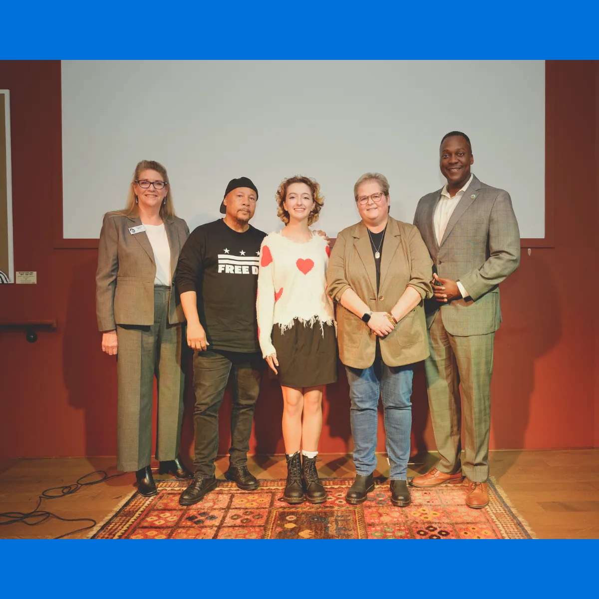 group of people pose for a picture together in front of a white screen